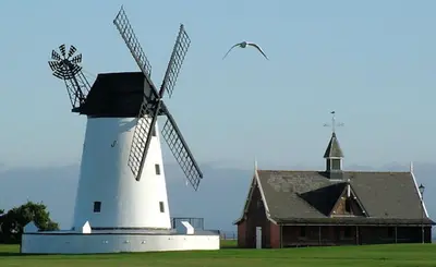 a white windmill next to a barn and a bird at Willow Lodge Hambleton in Poulton le Fylde