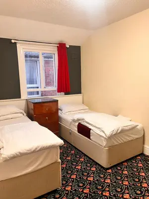 two beds in a room with a red window at The oxford Hotel in Blackpool