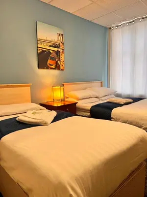 a hotel room with three beds and a painting on the wall at The oxford Hotel in Blackpool