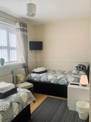 a hotel room with two beds and a chair at Be My Guest Liverpool - Ground Floor Apartment with Parking in Liverpool