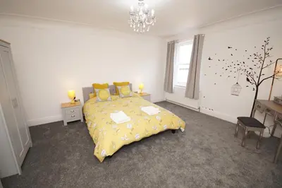 a bedroom with a bed with a yellow comforter at Grade 2 Listed Apartment, Southport Promenade in Southport