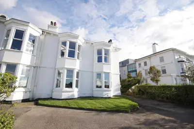 a white house with a lawn in front of it at Grade 2 Listed Apartment, Southport Promenade in Southport