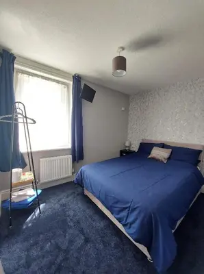 a bedroom with a blue bed and a window at The Clevedon in Blackpool
