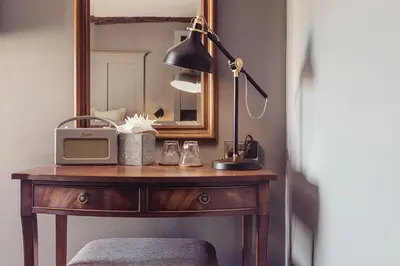 a table with a clock and a lamp and a mirror at The New Inn in Carnforth