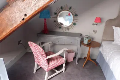 a bedroom with a bed and a chair and a mirror at The New Inn in Carnforth