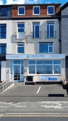 a white building with a sign on the front of it at Granada Apartments Queen's Promenade in Blackpool