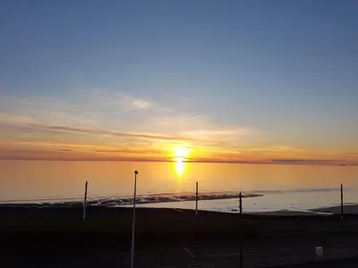 a sunset over the water with poles in the foreground at Granada Apartments Queen's Promenade in Blackpool