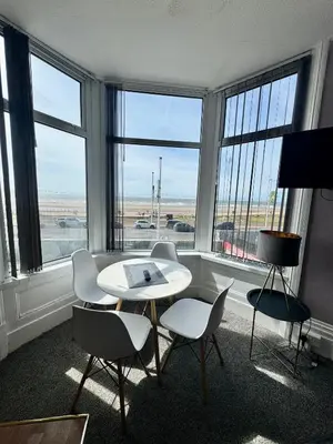 a room with a table and chairs and windows at On The Beach Apartments in Blackpool