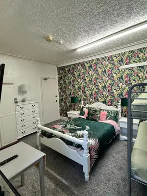 a bedroom with a bed with a floral wallpaper at On The Beach Apartments in Blackpool