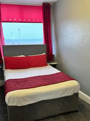 a bedroom with a bed with red pillows and a window at On The Beach Apartments in Blackpool