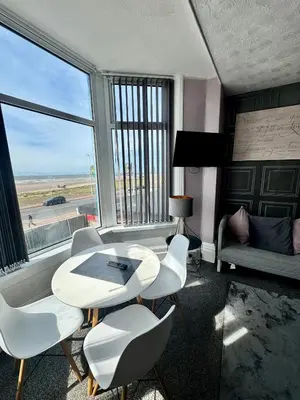 a room with a table and chairs and a large window at On The Beach Apartments in Blackpool