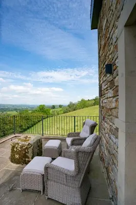 a patio with four chairs and a stone wall at The Chicken Shed at Knowle Top in Clitheroe