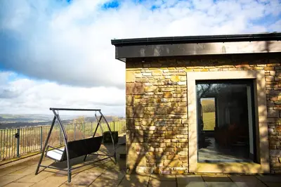 a patio with a swing and a building at The Chicken Shed at Knowle Top in Clitheroe