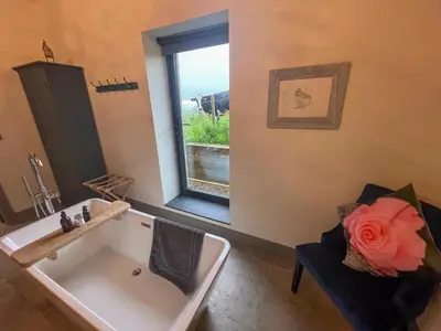 a bathroom with a white tub and a window at The Chicken Shed at Knowle Top in Clitheroe