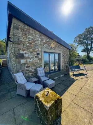 a brick building with a group of chairs and a rock at The Chicken Shed at Knowle Top in Clitheroe