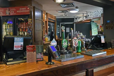 a bar with a counter with a telephone and alcohol at Lea Gate by Greene King Inns in Preston