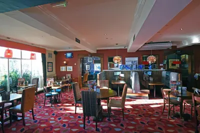 a restaurant with tables and chairs and a bar at Lea Gate by Greene King Inns in Preston
