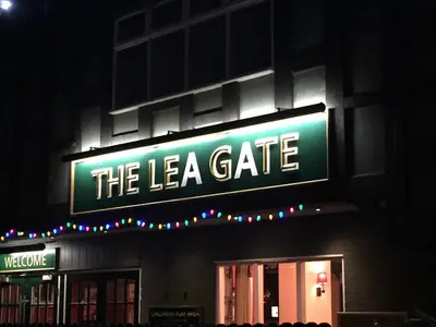 a sign for the la gate on a building at night at Lea Gate by Greene King Inns in Preston