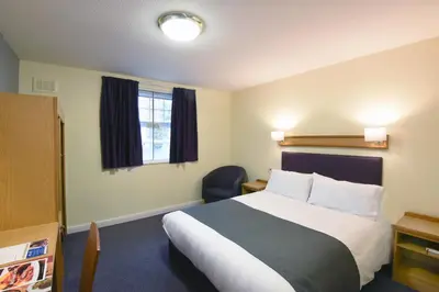 a hotel room with a bed and a chair at The Mount by Greene King Inns in Wigan