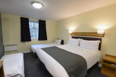 a hotel room with two beds and a window at The Mount by Greene King Inns in Wigan