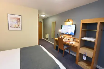 a room with a bed and a desk with a television at The Mount by Greene King Inns in Wigan