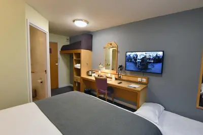 a hotel room with a bedroom with a desk and a bed at The Mount by Greene King Inns in Wigan