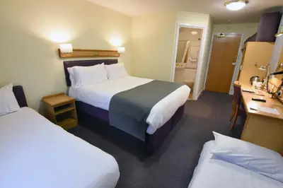 a hotel room with two beds and a bathroom at The Mount by Greene King Inns in Wigan