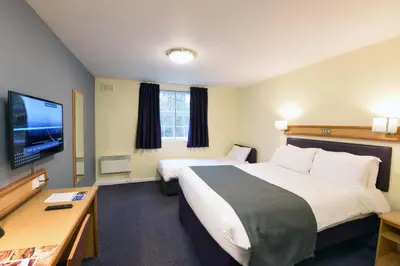 a hotel room with two beds and a flat screen tv at The Mount by Greene King Inns in Wigan