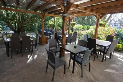 a patio with tables and chairs under a pavilion at The Mount by Greene King Inns in Wigan