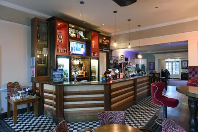 a bar in a restaurant with tables and chairs at The Mount by Greene King Inns in Wigan