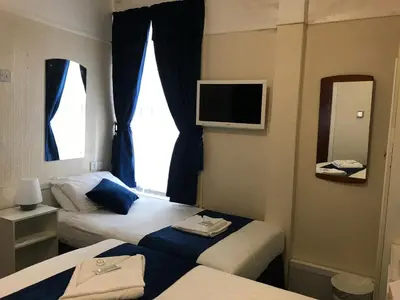 a hotel room with two beds and a television at The Feathers Hotel in Blackpool