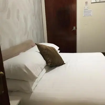 a bed with white sheets and a pillow on it at The Feathers Hotel in Blackpool