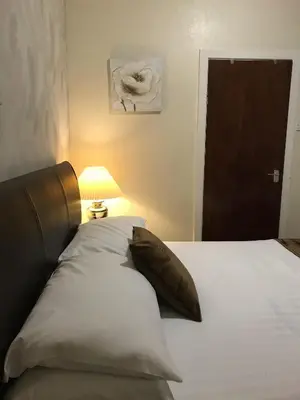 a bed with a pillow and a lamp next to a door at The Feathers Hotel in Blackpool