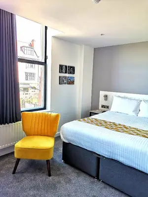 a bedroom with a bed and a yellow chair at Mode Hotel Lytham in Lytham St Annes