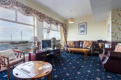a living room with furniture and a large window at Maples Hotel in Blackpool