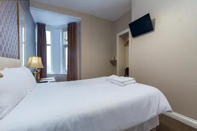 a hotel room with a white bed and a television at Maples Hotel in Blackpool