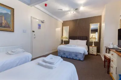 a hotel room with two beds and a sink at Maples Hotel in Blackpool