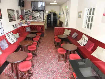 a restaurant with red couches and stools and tables at Charnley Gold in Blackpool