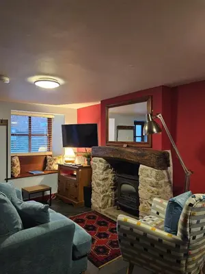 a living room with a couch and a stone fireplace at Causeway Cottage in Cartmel