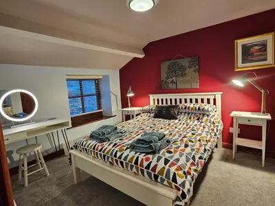 a bedroom with a bed and a desk and a mirror at Causeway Cottage in Cartmel