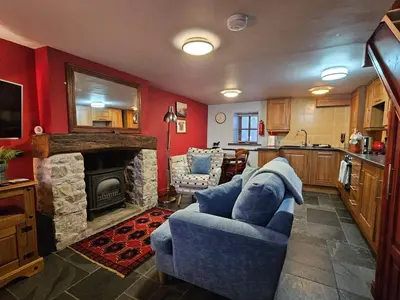 a living room with a blue couch and a stone fireplace at Causeway Cottage in Cartmel