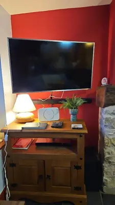 a desk with a large television on a red wall at Causeway Cottage in Cartmel