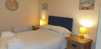 a bedroom with a white bed with two lamps on tables at Eden Rose Cottage hot-tub jacuzzi morecambe-bay in Morecambe