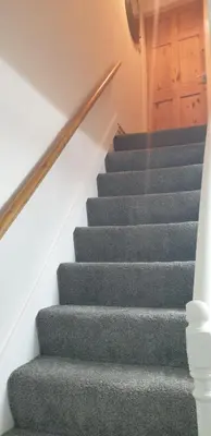 a staircase with grey carpet and a wooden door at Eden Rose Cottage hot-tub jacuzzi morecambe-bay in Morecambe