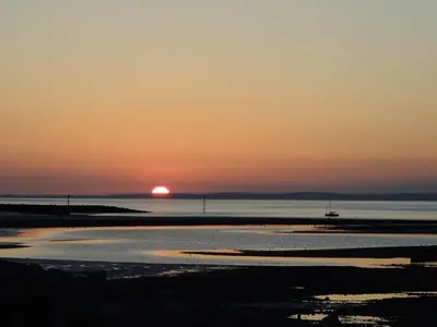 a sunset over the water with the sun setting at Eden Rose Cottage hot-tub jacuzzi morecambe-bay in Morecambe