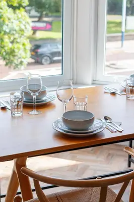 a wooden table with glasses and plates on it at Hy Lytham St Anne's in Lytham St Annes
