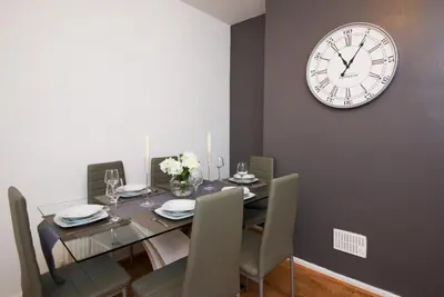 a dining room with a table and a clock on the wall at Stylish and Comfortable Home Away From Home in Liverpool