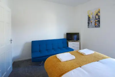 a bedroom with a blue couch and a bed at Stylish and Comfortable Home Away From Home in Liverpool