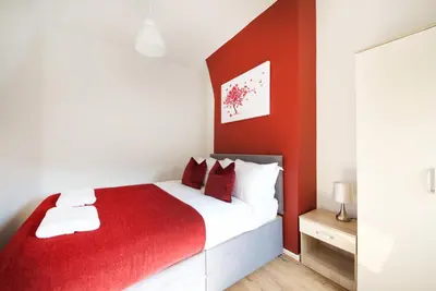 a bedroom with a red and white bed and a mirror at Stylish and Comfortable Home Away From Home in Liverpool
