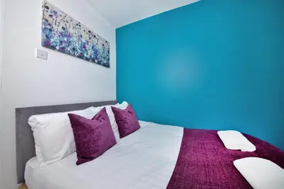a bedroom with a bed with purple and white pillows at Stylish and Comfortable Home Away From Home in Liverpool